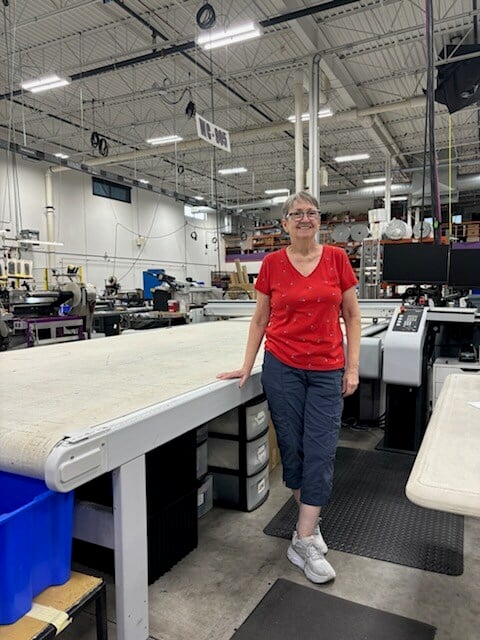 Annette posing with a fabric cutting machine