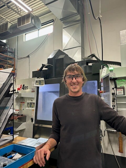 Luke posing in front of a CNC machine